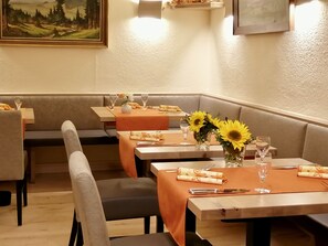 A restaurant with booths and tables, each set with cutlery, glasses, and sunflowers. - Hotel-Gasthaus zur Eiche (Hausach)