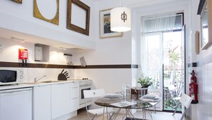 Uma cozinha moderna com armários brancos, uma mesa de jantar com cadeiras e uma grande janela com vista para o exterior.