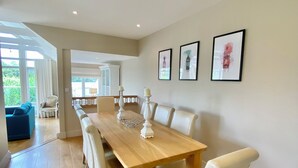 A spacious dining area with a wooden table and white upholstered chairs. - Beautiful 4 bed lakeside lodge in the Cotswolds. Private deck & STUNNING views (South Cerney)