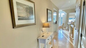 A hallway with wooden flooring, a white console table with a lamp, and a framed picture on the wall. - Beautiful 4 bed lakeside lodge in the Cotswolds. Private deck & STUNNING views (South Cerney)