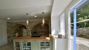 A kitchen with a stone wall, wooden countertop, and built-in cabinets.