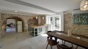 A spacious kitchen with a stone archway, a dining area with a wooden table, and a view of the outdoors.