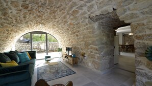 A stone-walled room with a sofa, a coffee table, and a TV.