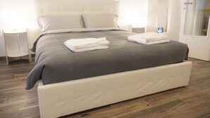 Un dormitorio moderno con una cama grande, dos mesitas de noche y un espejo amplio.
