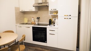 Una cocina moderna con gabinetes blancos, una campana extractora de acero inoxidable, horno empotrado y un lavamanos.