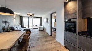 A modern kitchen with a wooden dining table, chairs, and a built-in oven. - Panorama Living Dolomites (Rio di Pusteria)