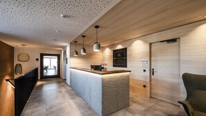 A modern reception area with a wooden reception desk, pendant lighting, and a sign reading "Panoramaliving." - Panorama Living Dolomites (Rio di Pusteria)