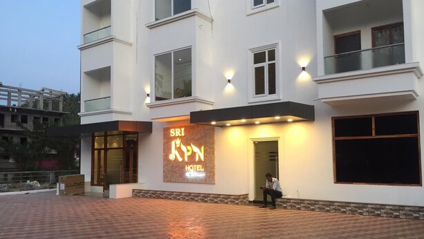 Ein Hotel Eingang mit einem Schild, auf dem 'Sri KPN Hotel' steht, und einer Person, die auf den Stufen sitzt.