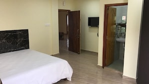 Ein Hotelzimmer mit einem Bett, einem Fernseher und einem durch eine offene Tür einsehbaren Badezimmer.