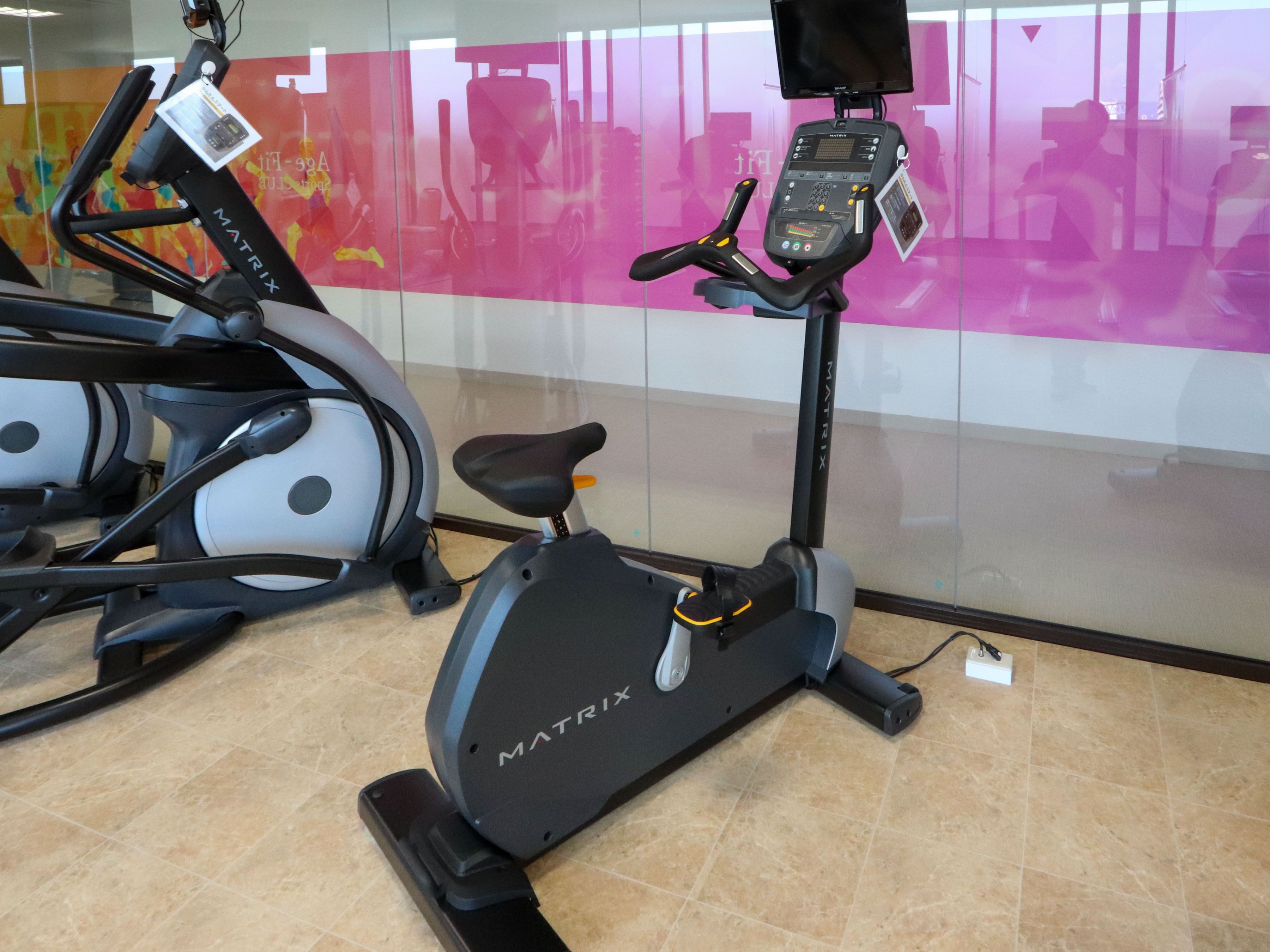 Una bicicleta estática con pantalla digital y una pantalla instalada en la pared.