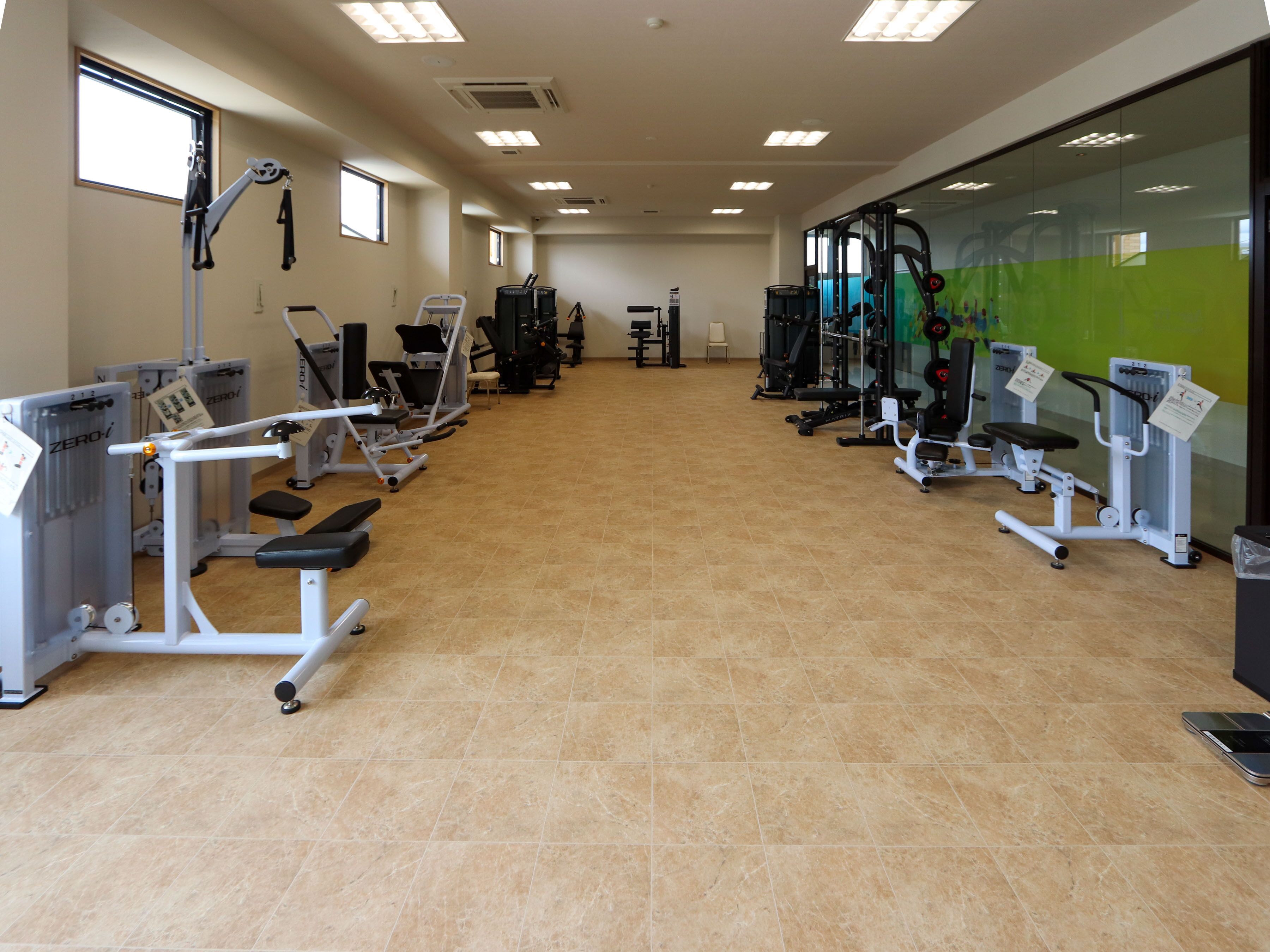 A gym with various exercise equipment, including treadmills and weight machines, arranged in rows.