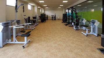 A gym with various exercise equipment, including treadmills and weight machines, arranged in rows.