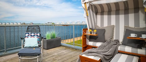 A deck with a lounge chair, a small sofa, and a canopy bed.