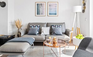 A modern living room with a grey sofa, a round coffee table, and a floor lamp.