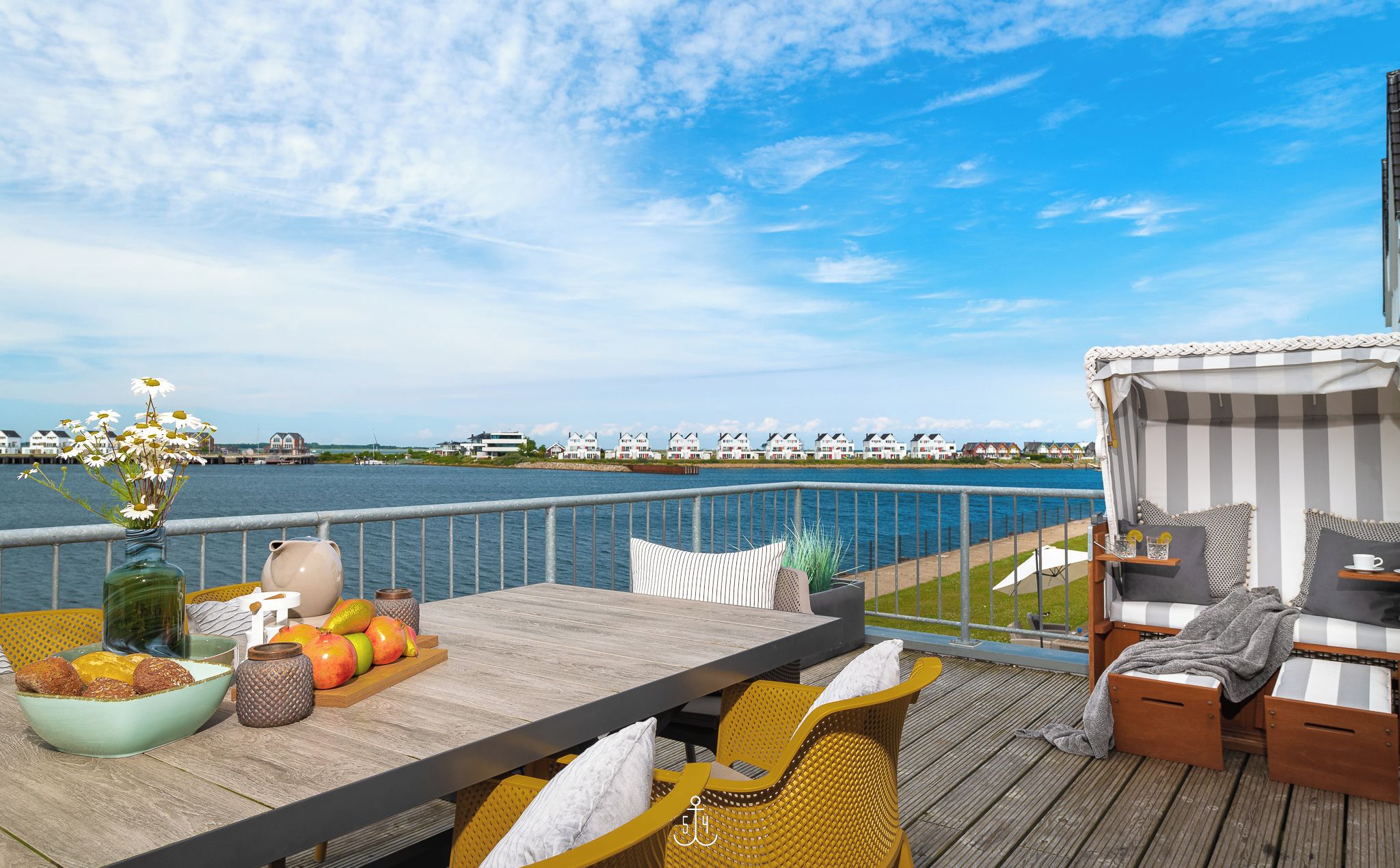 Une terrasse avec une table, des chaises et une vue sur l’eau.