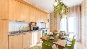 Eine moderne Küche mit Holzschränken, einer eingebauten Mikrowelle und einem Essbereich mit einem Holztisch und grünen Stühlen.