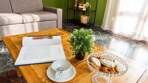 Ein Holztisch mit einem Buch, einer kleinen Topfpflanze, einer weißen Tasse und einer Korb mit Keksen.