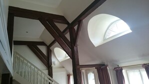 Ein Zimmer mit schrägen Wänden, Holzbalken, einer Treppe und einem Oberlicht.