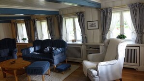 Ein Zimmer mit blauer und weißer Farbgestaltung, ausgestattet mit einer Couch, Sesseln und einem kleinen Tisch.