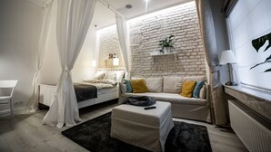 Un dormitorio con cama, mesita de noche y ventana con cortinas.
