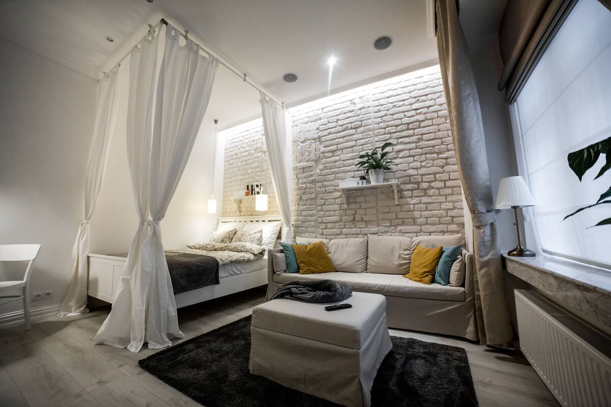 A bedroom with a bed, bedside table, and a window with curtains.