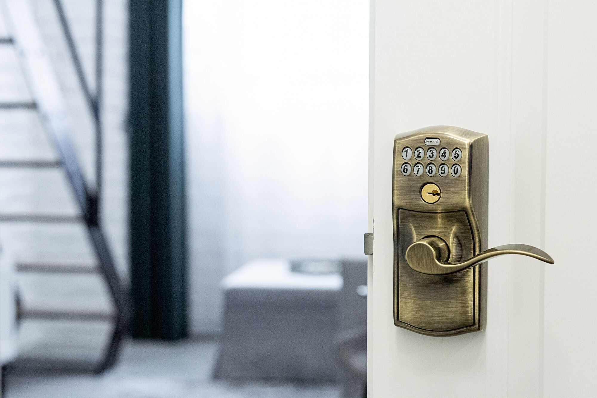 A brass door lock with a numeric keypad and a keyhole.