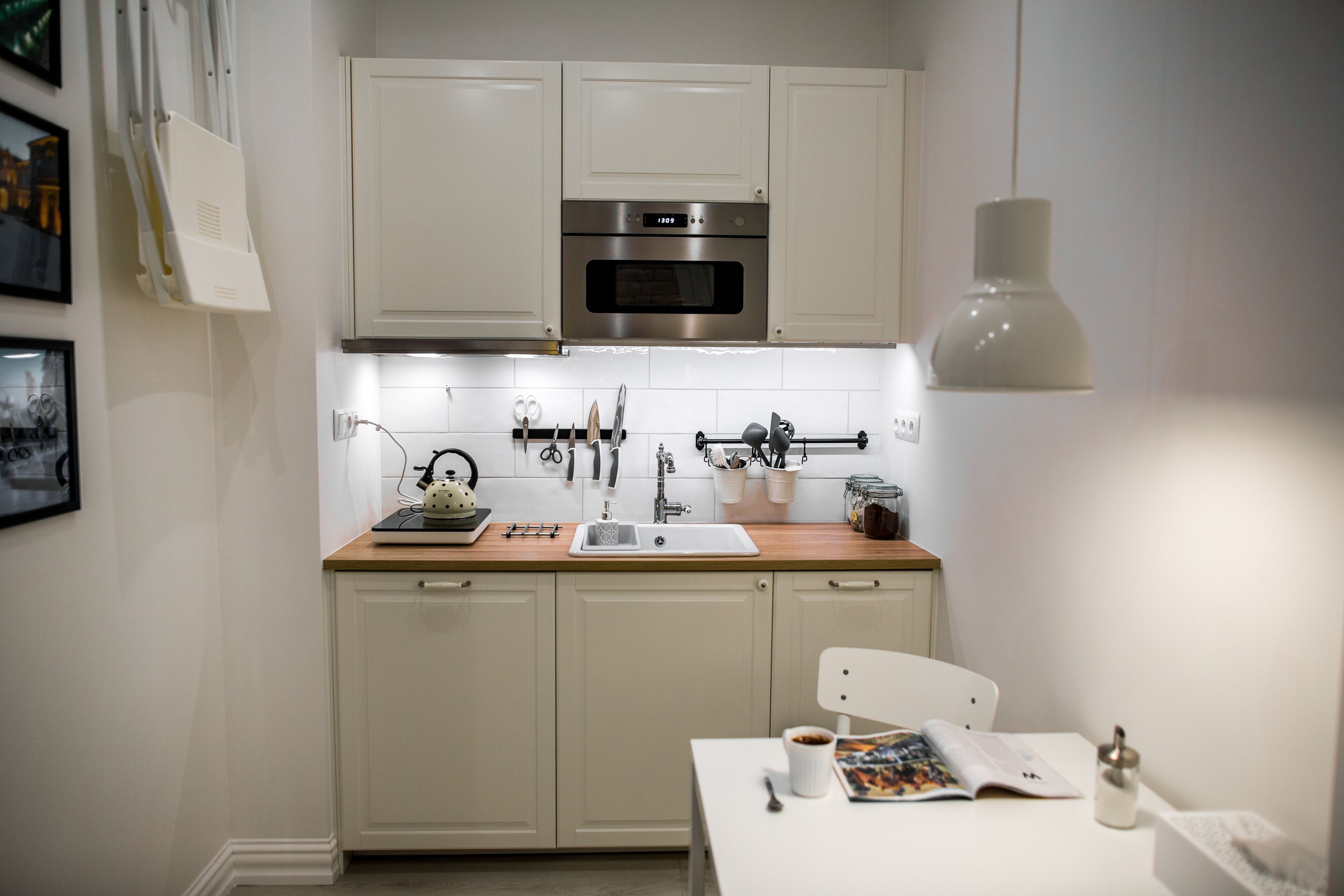 Une cuisine moderne avec des meubles blancs, un four en acier inoxydable et un plan de travail en bois.