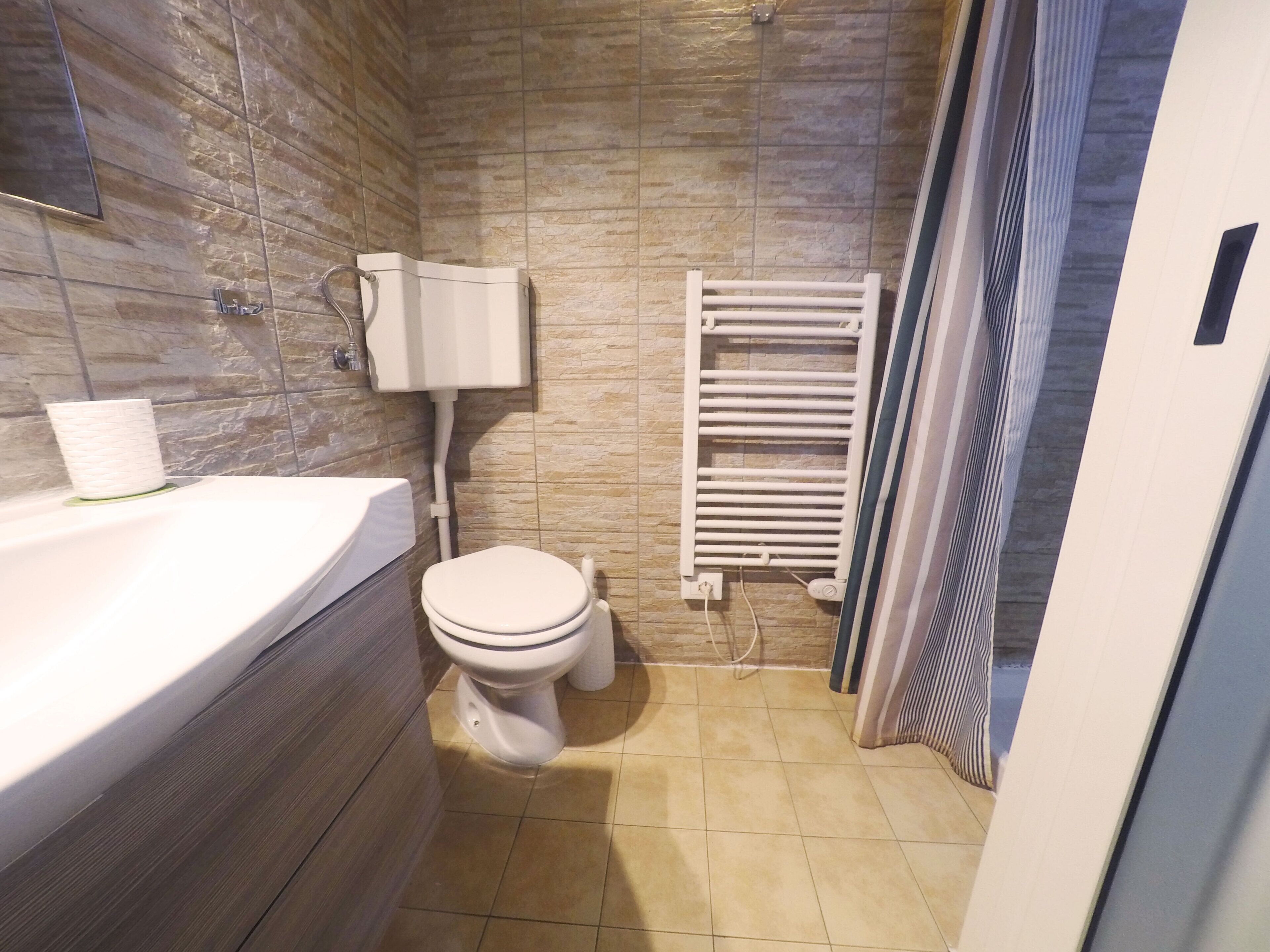 Un baño con inodoro, bañera y perchero para toallas.