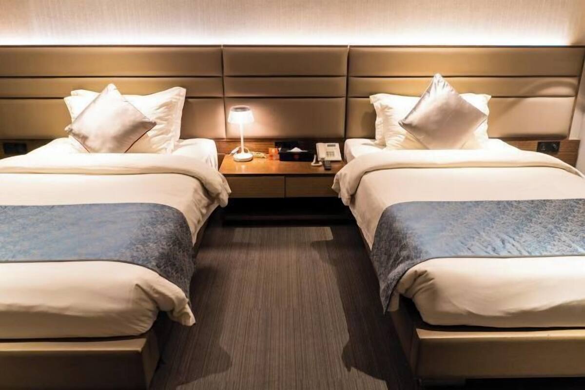 Habitación de hotel con dos camas, una mesita de noche, una lámpara y un teléfono.