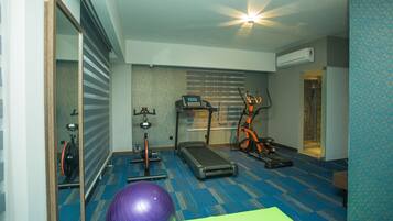 A fitness room with exercise equipment, a mirrored wall, and a blue carpet.