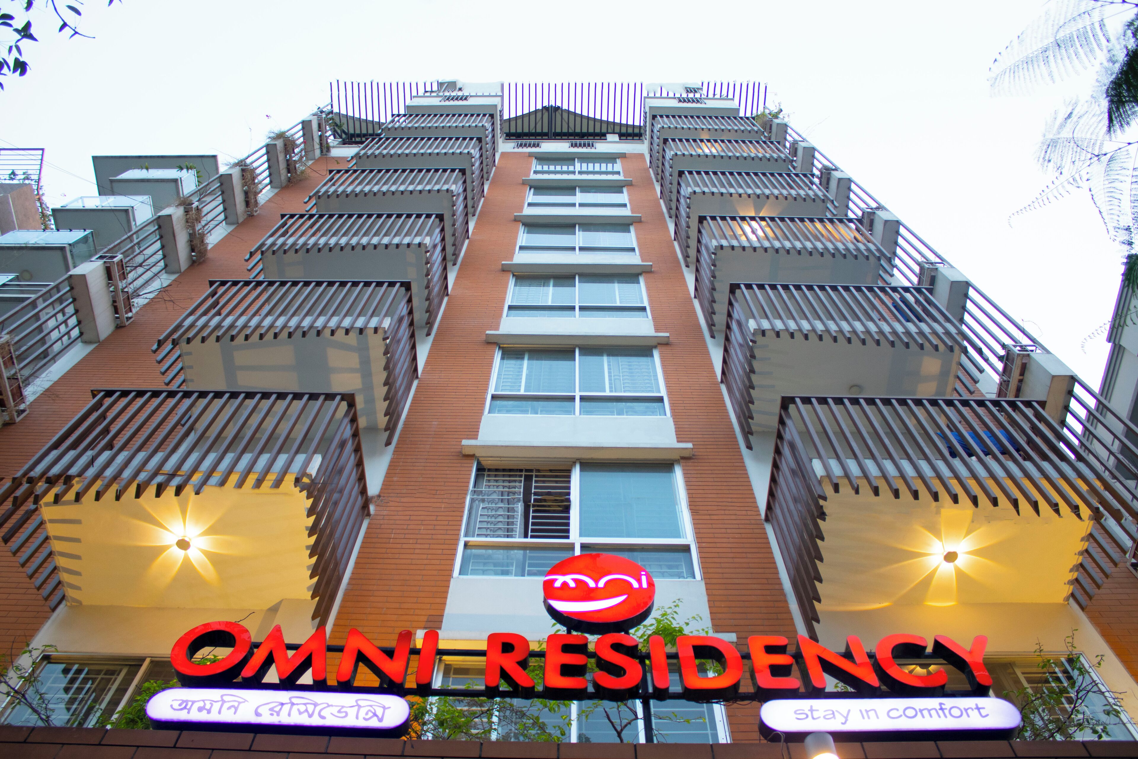 Un edificio de varios pisos con balcones y un letrero que dice "OMNI RESIDENCY".