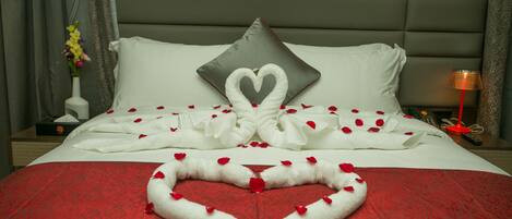 Une chambre d’hôtel avec un lit parfaitement fait, une disposition de serviettes en forme de cœur et un oreiller en forme de cœur.