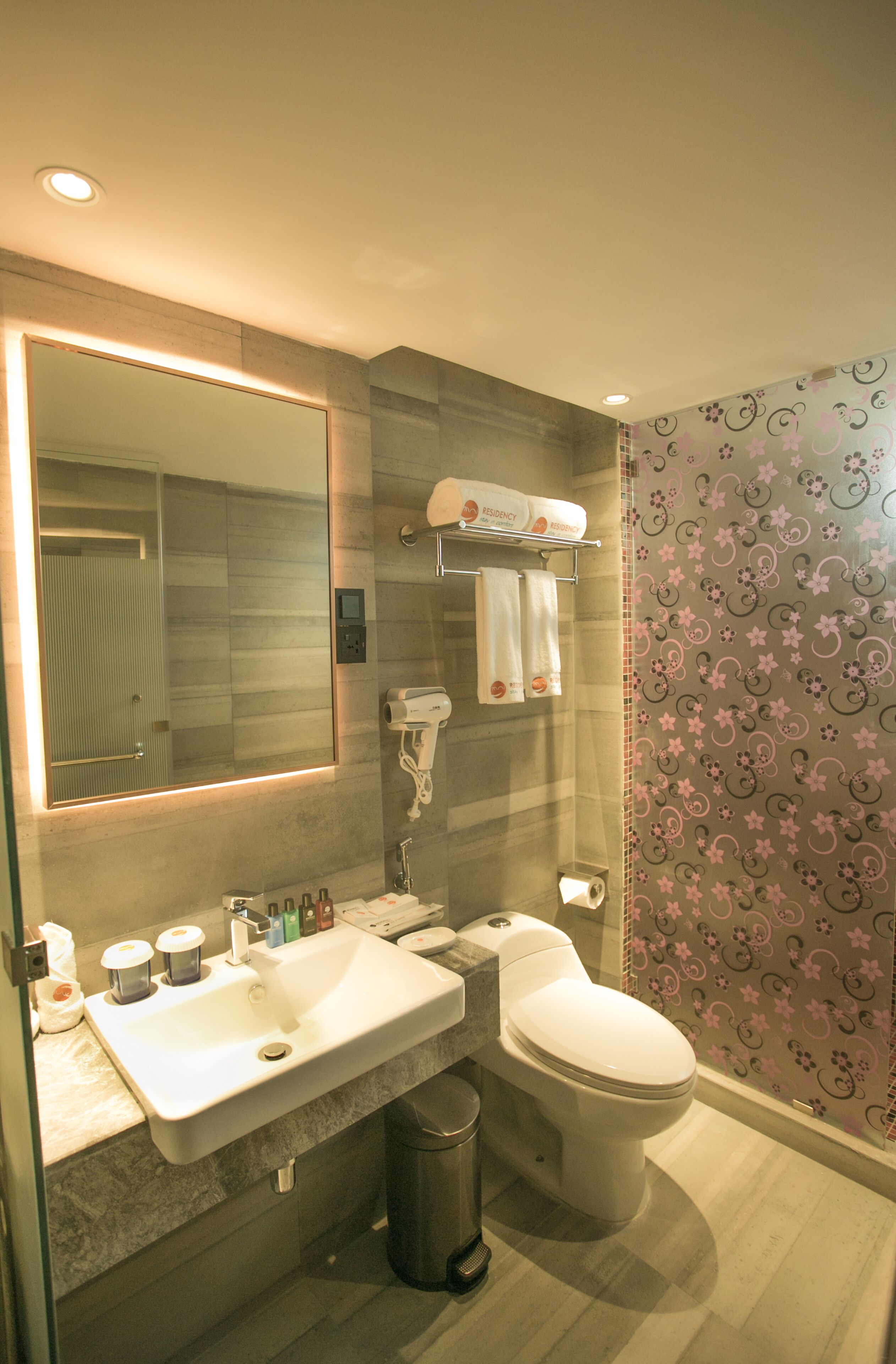 Une salle de bain moderne avec un grand miroir, un lavabo, des toilettes et un sèche-cheveux.