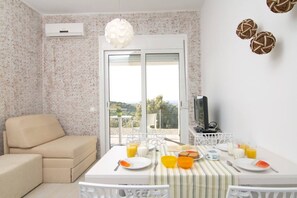 Un'area pranzo con un tavolo apparecchiato per la colazione, un divano e una TV su un mobile.
