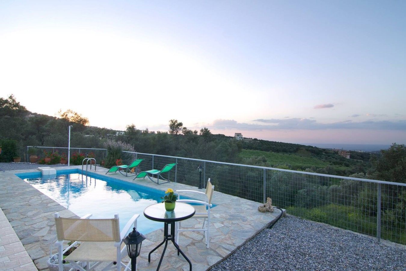 A swimming pool with lounge chairs, a table, and a view of the landscape.
