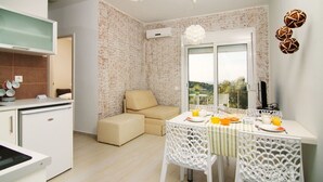Eine moderne Küche mit Essbereich, einer Couch und Blick durch das Fenster.