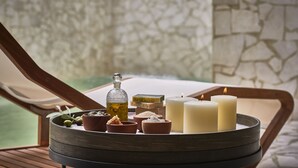 Un plateau avec des bougies, une bouteille et de petits bols de sels de bain, le tout posé sur une table en bois.