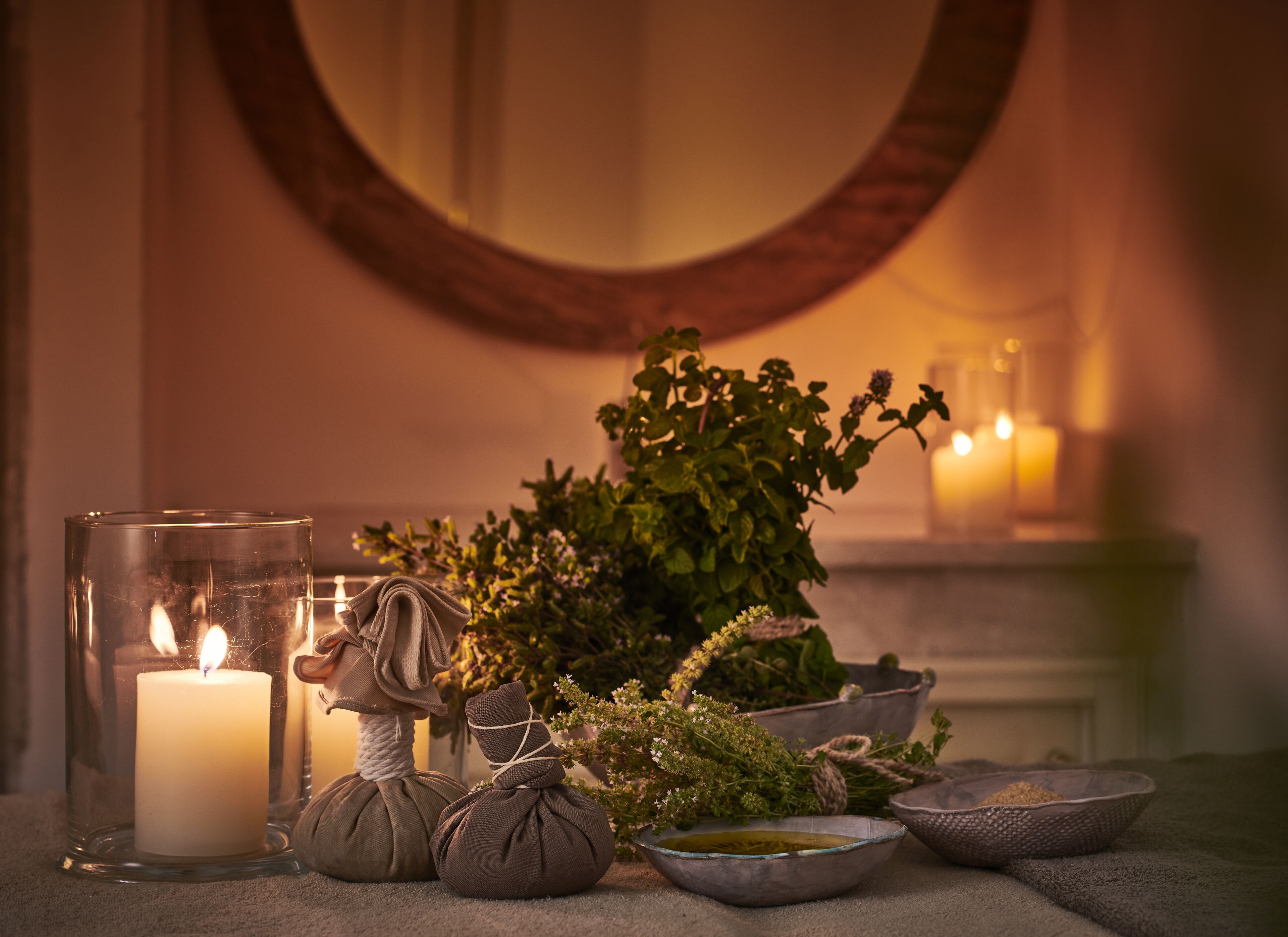 A room with a lit candle, a mirror, and various decorative items including a plant and bowls.