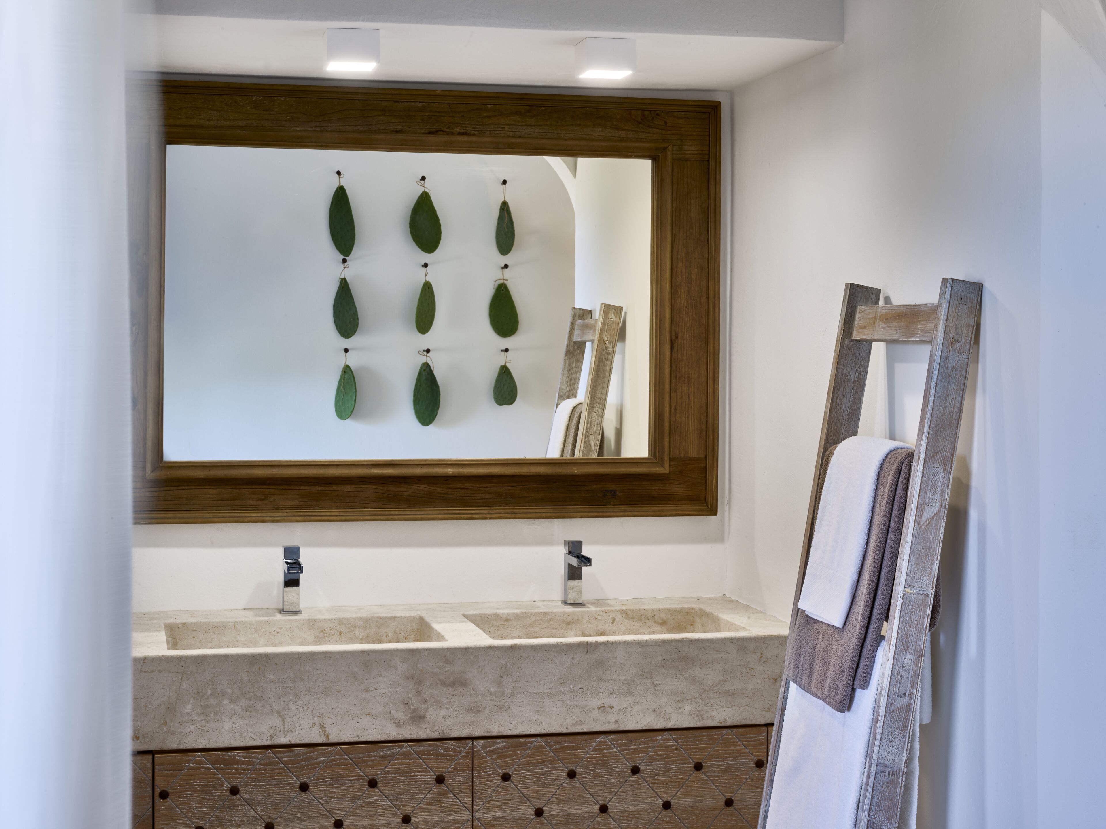 Un bagno con uno specchio grande, due lavandini e un armadietto in legno.