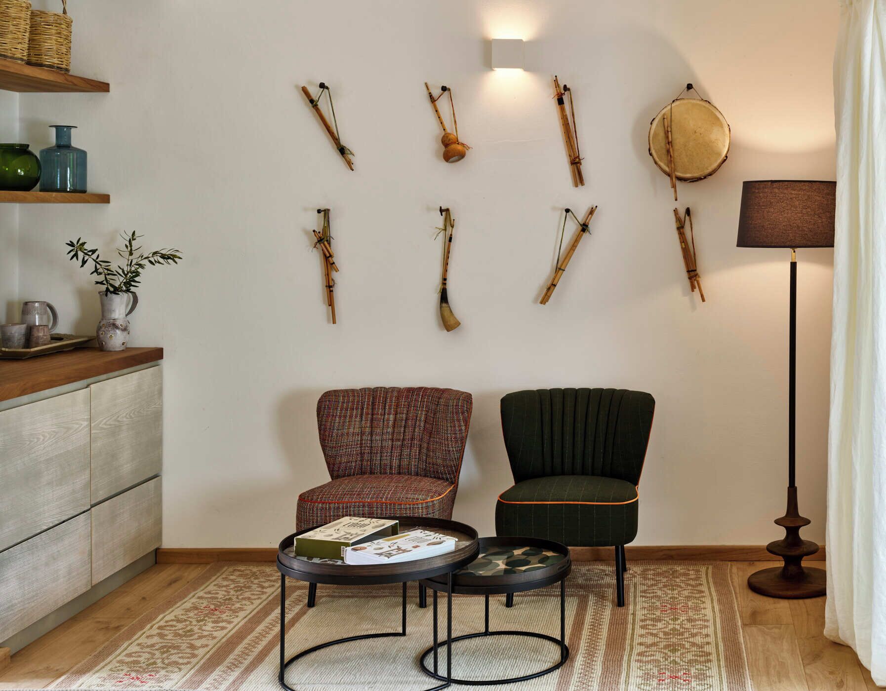 Una sala de estar con dos sillones, una mesa de centro, una lámpara e instrumentos musicales colgados en la pared.