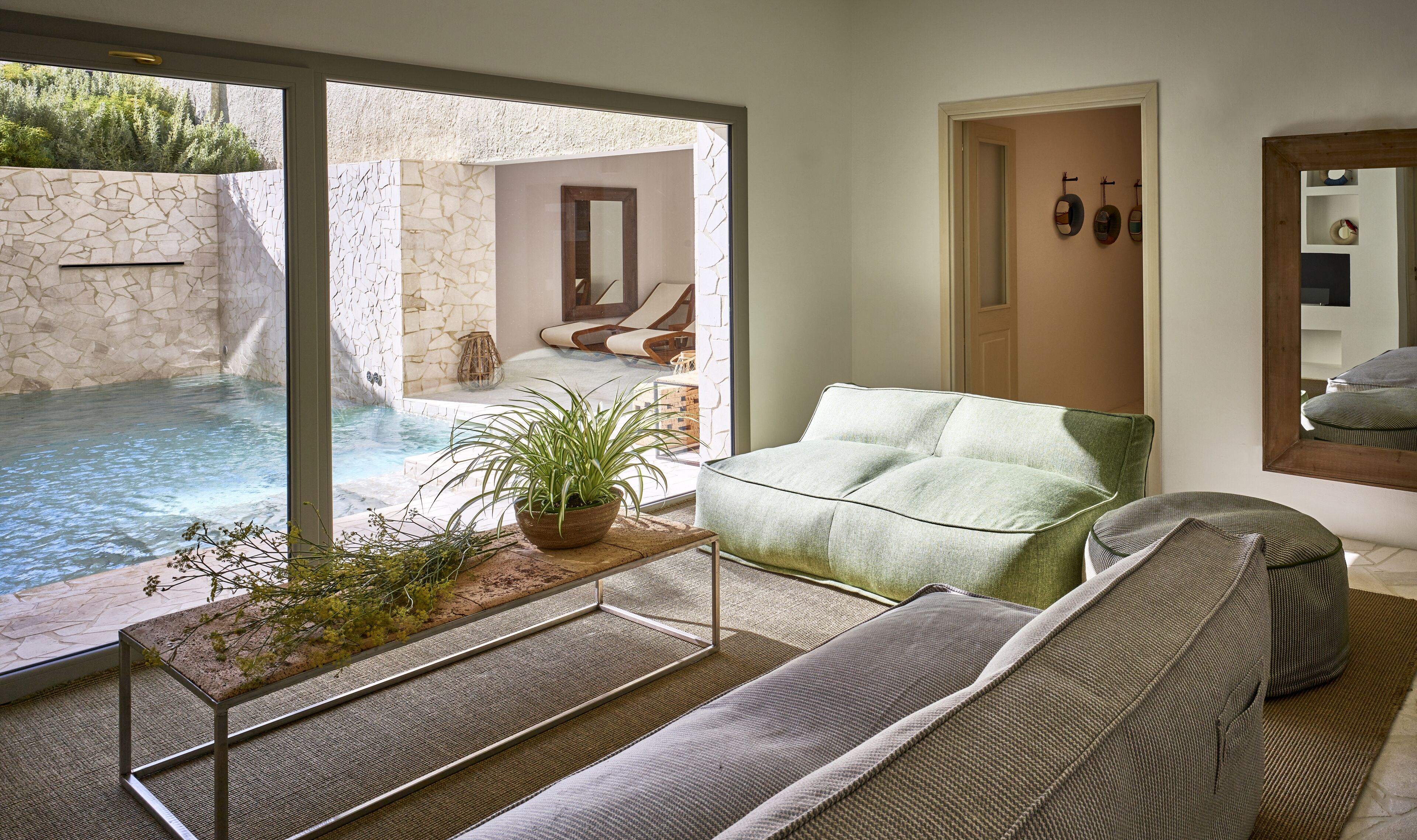 Un salon moderne doté d’une grande porte-fenêtre coulissante donnant accès à un espace extérieur privé avec un jacuzzi.