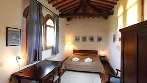 A bedroom with a wooden ceiling, a bed with towels, a desk, a chair, and a lamp. - 2bedrooms apartment with pool in the Chianti area, organic farm (Florence)