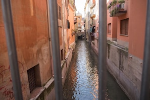 A narrow waterway flanked by buildings with balconies, a visible window, and a metal railing. - Casa Bella River (Bologna)