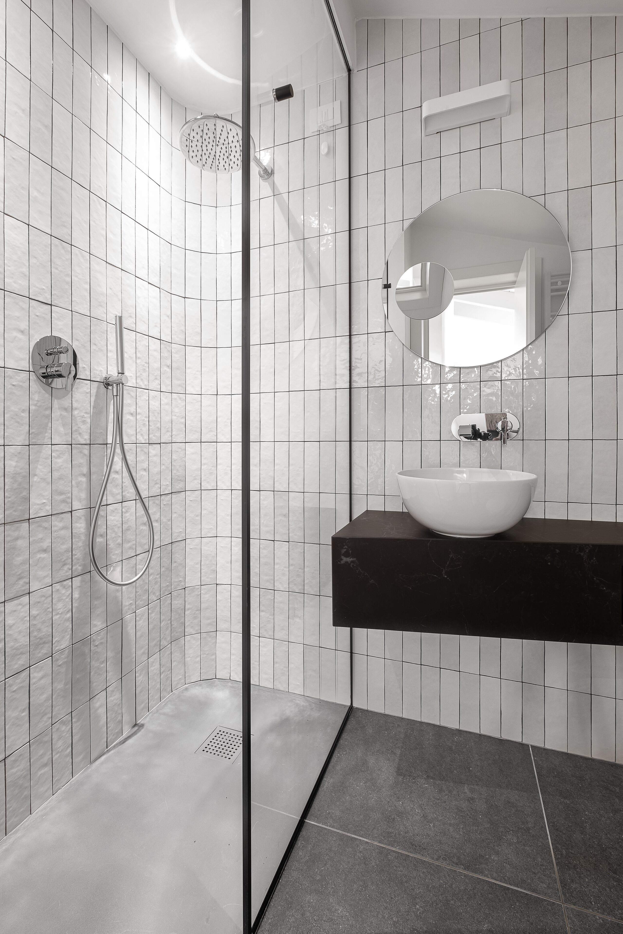 Une salle de bain moderne avec une douche à parois de verre, un lavabo blanc et un miroir au-dessus.