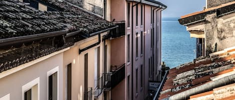 Una calle estrecha flanqueada por edificios, con vista al mar y una escalera que desciende.
