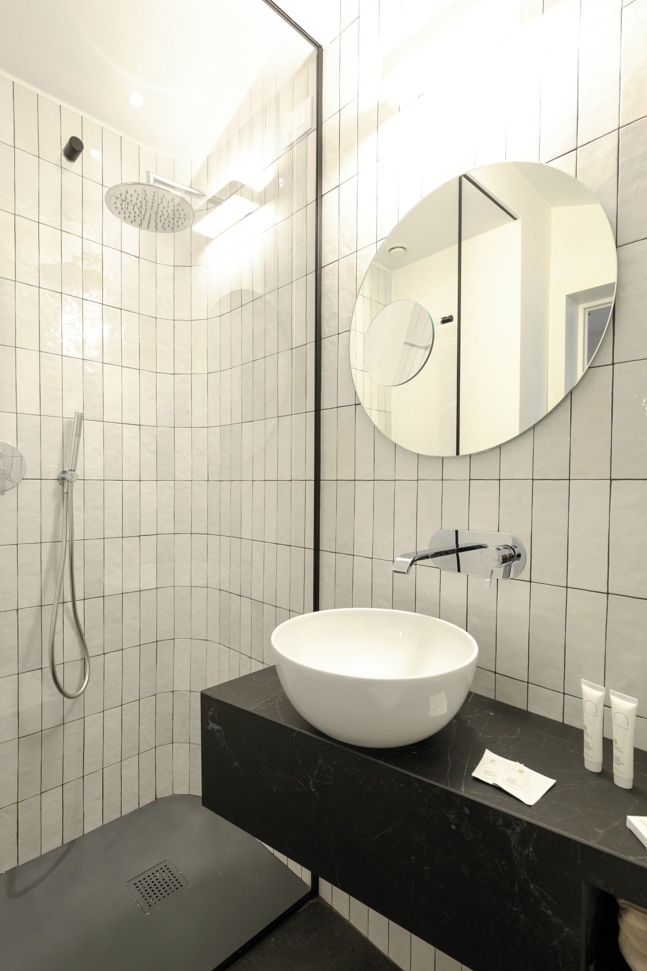 A modern bathroom with a white sink, a large mirror, and a shower.