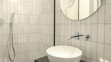 A modern bathroom with a white sink, a large mirror, and a shower.