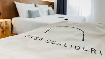 Et hotelværelse med en seng og en sengegavl, samt en taske med teksten "CASA SCALIGERI".