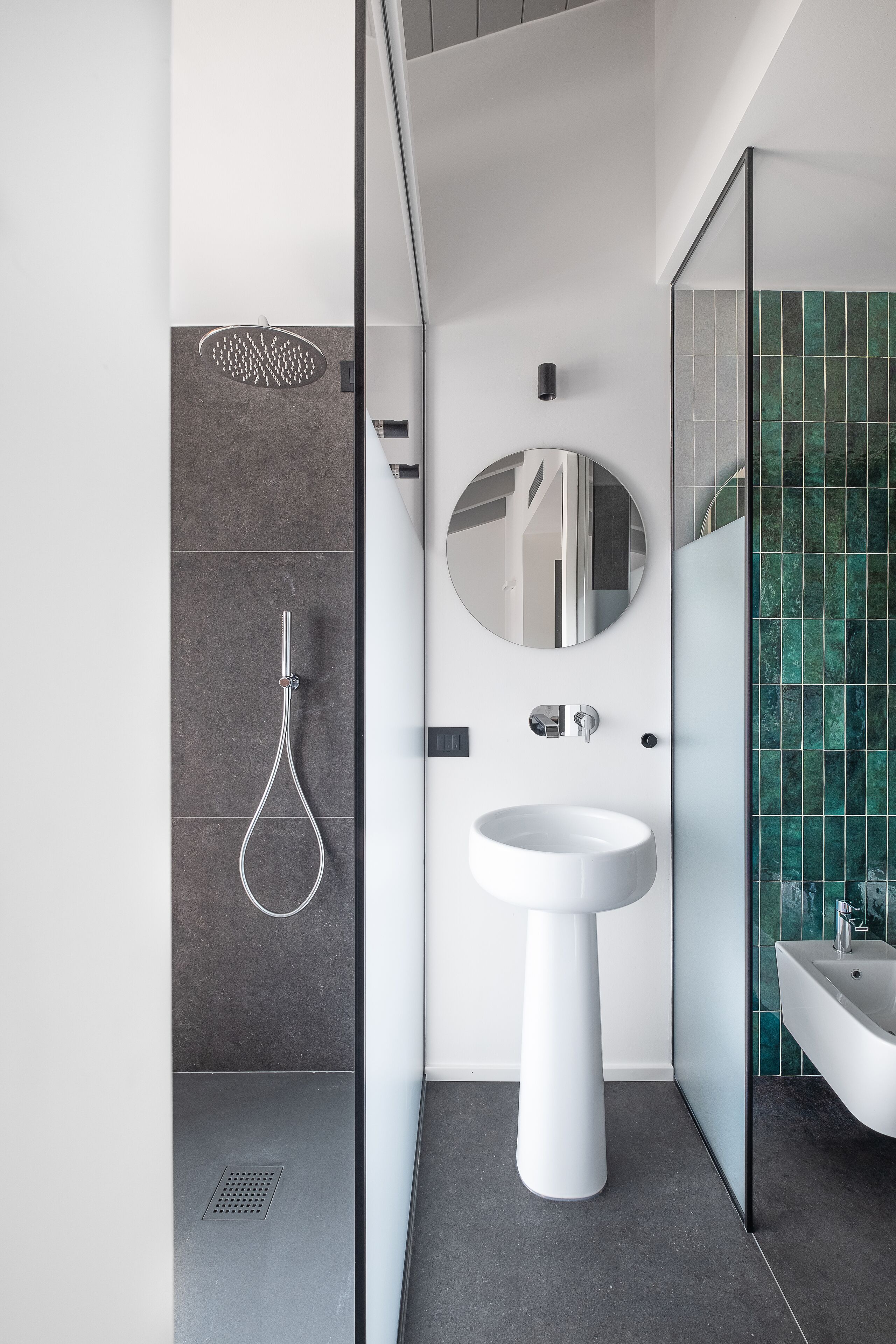 Un baño moderno con ducha, lavamanos y espejo.
