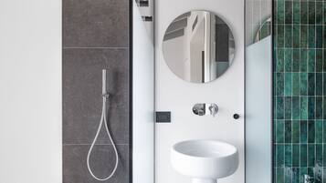 Un baño moderno con ducha, lavamanos y espejo.
